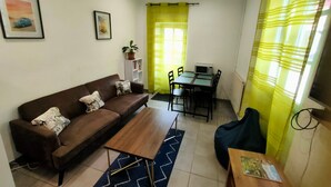 Un salon comprenant un canapé, une table basse, une table à manger, des chaises et un four à micro-ondes.