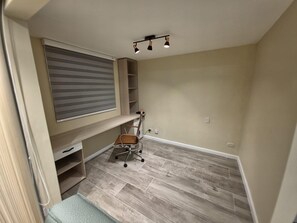 Een kamer met een inbouwkbank, een bureau, een stoel en een plafondlamp.