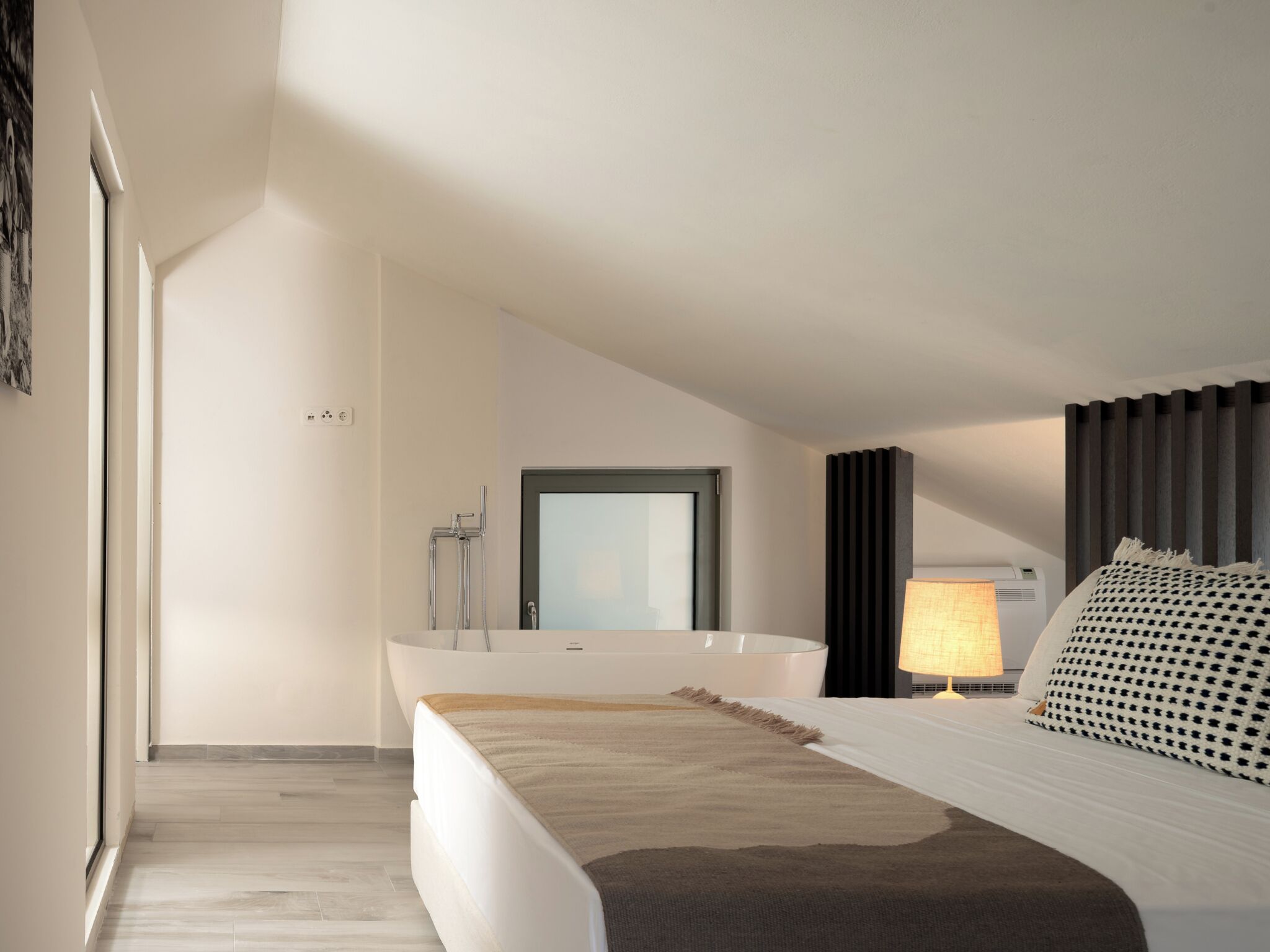 Een moderne slaapkamer met een groot bed, een badkuip en een raam.