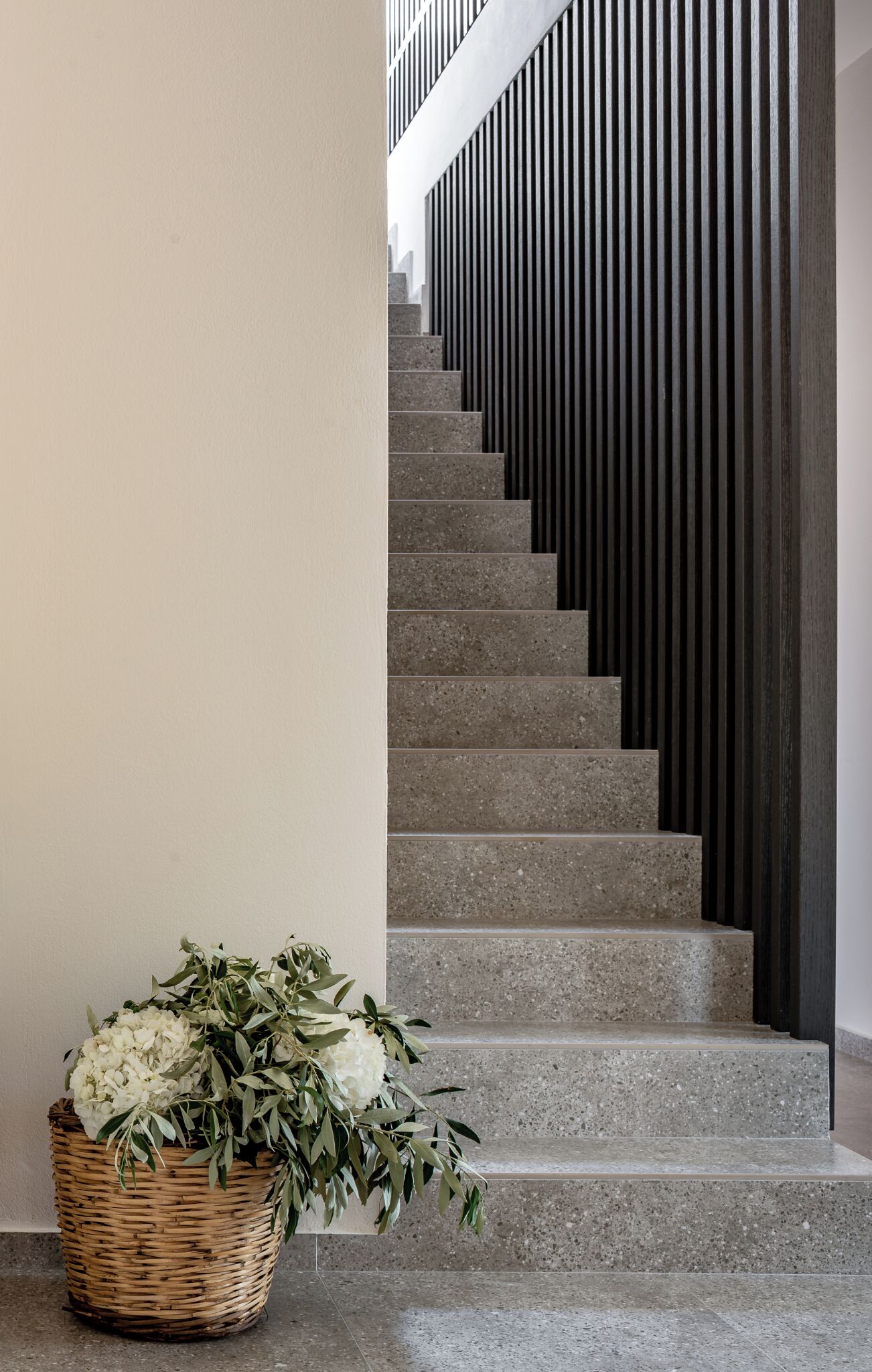 A staircase with a basket of white flowers at the base.