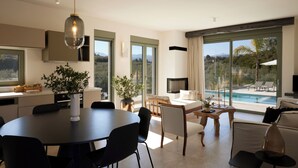 Ein modernes Interieur mit Essbereich, Sitzgelegenheiten, einem Fernseher und Blick auf einen Swimmingpool.