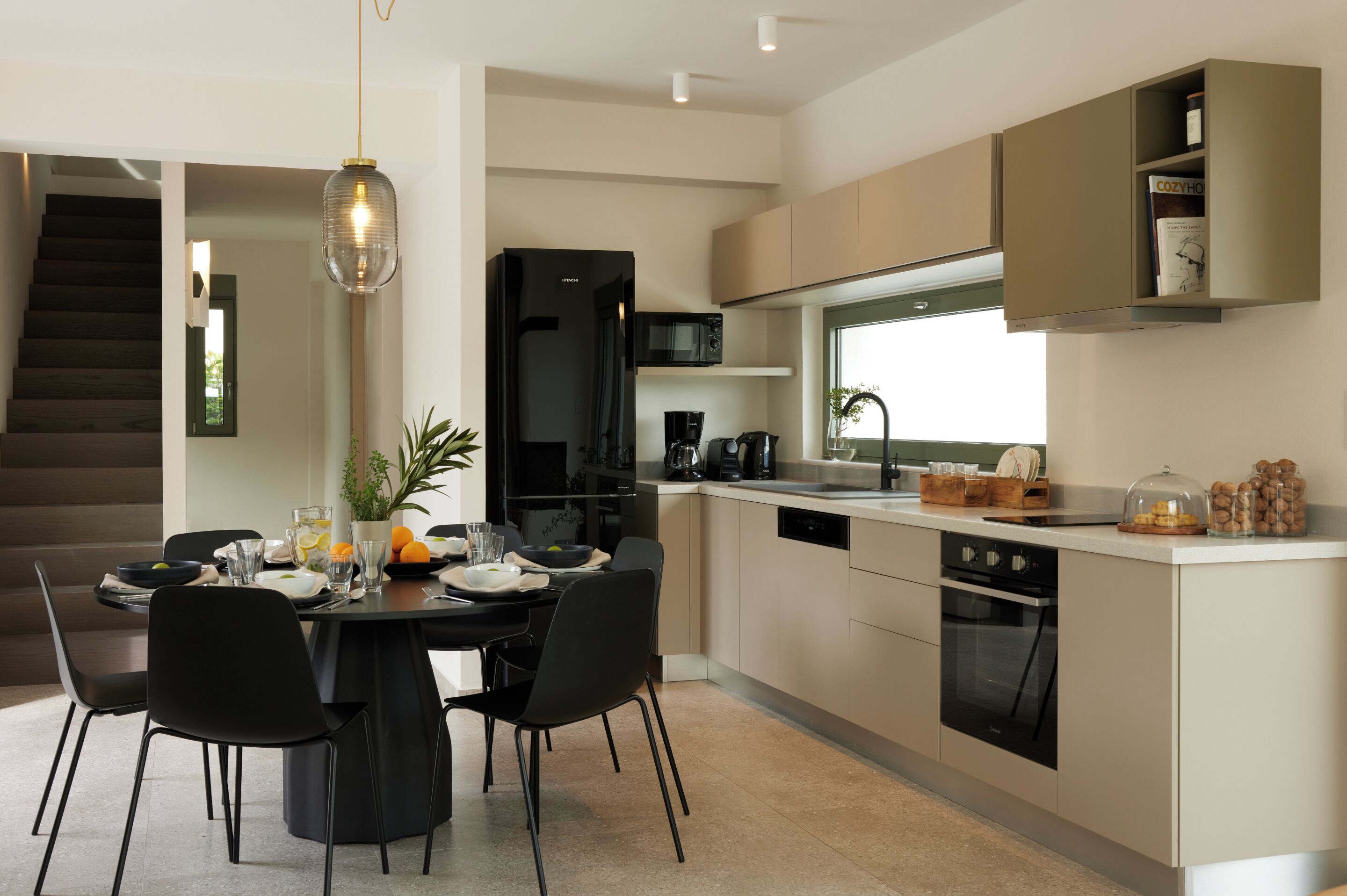 Una cocina moderna con comedor, una escalera y electrodomésticos integrados.