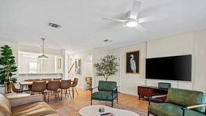 A living room with a sofa, coffee table, chairs, a television, and a dining area. - Fly Creek Collection - Sunset Perch (Fairhope)