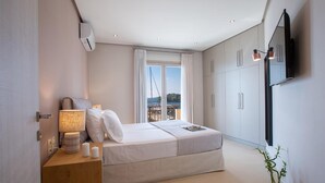 Ein Schlafzimmer mit Bett, Nachttisch, Lampe und einem an der Wand befestigten Fernseher.
