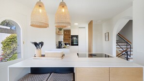 Een moderne keuken met een centraal eiland, hanglampen en uitzicht op de omgeving.