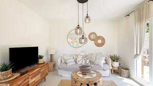 Een woonkamer met een televisie, bank, salontafel en decoratieve objecten.