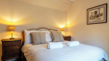 A neatly made bed with pillows and a blanket, two bedside lamps, a nightstand, and a framed picture on the wall.