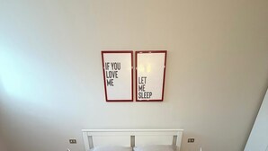 A neatly made bed with pillows and folded towels, two bedside tables with lamps, and two framed wall art pieces.