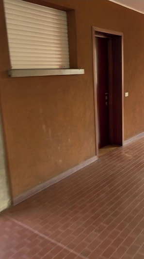 A hallway with a door, a window with blinds, and a wall-mounted shelf. - Cozy little house very close to Areoporto, Fiera di Bergamo and hospitals (Seriate)