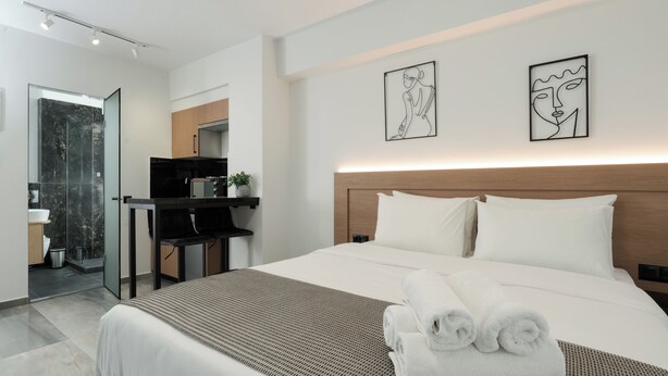 Una habitación de hotel moderna con una cama grande, un escritorio y un baño.