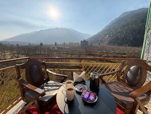 A balcony with a table set for two, including a coffee pot, cups, and chocolate bars. - Hotel Mount View By Oscar Hotels  (Manali)
