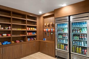 A well-organized pantry with shelves stocked with snacks and beverages, and a refrigerator filled with drinks.