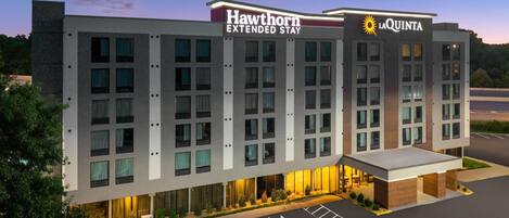A multi-story hotel with 'Hawthorn Extended Stay' and 'La Quinta' branding, featuring a modern design with large windows and a parking lot.