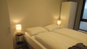 Een slaapkamer met een bed, twee bedlampen, een kledingkast en een raam.