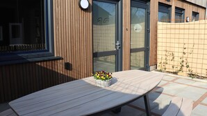 A wooden table with a basket of flowers, a door with a number, and a fence with climbing plants. - Luxury Waterfront Villa (Leons)