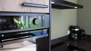 A modern kitchen with a built-in oven, a coffee maker, and a wooden cabinet. - Luxury Waterfront Villa (Leons)