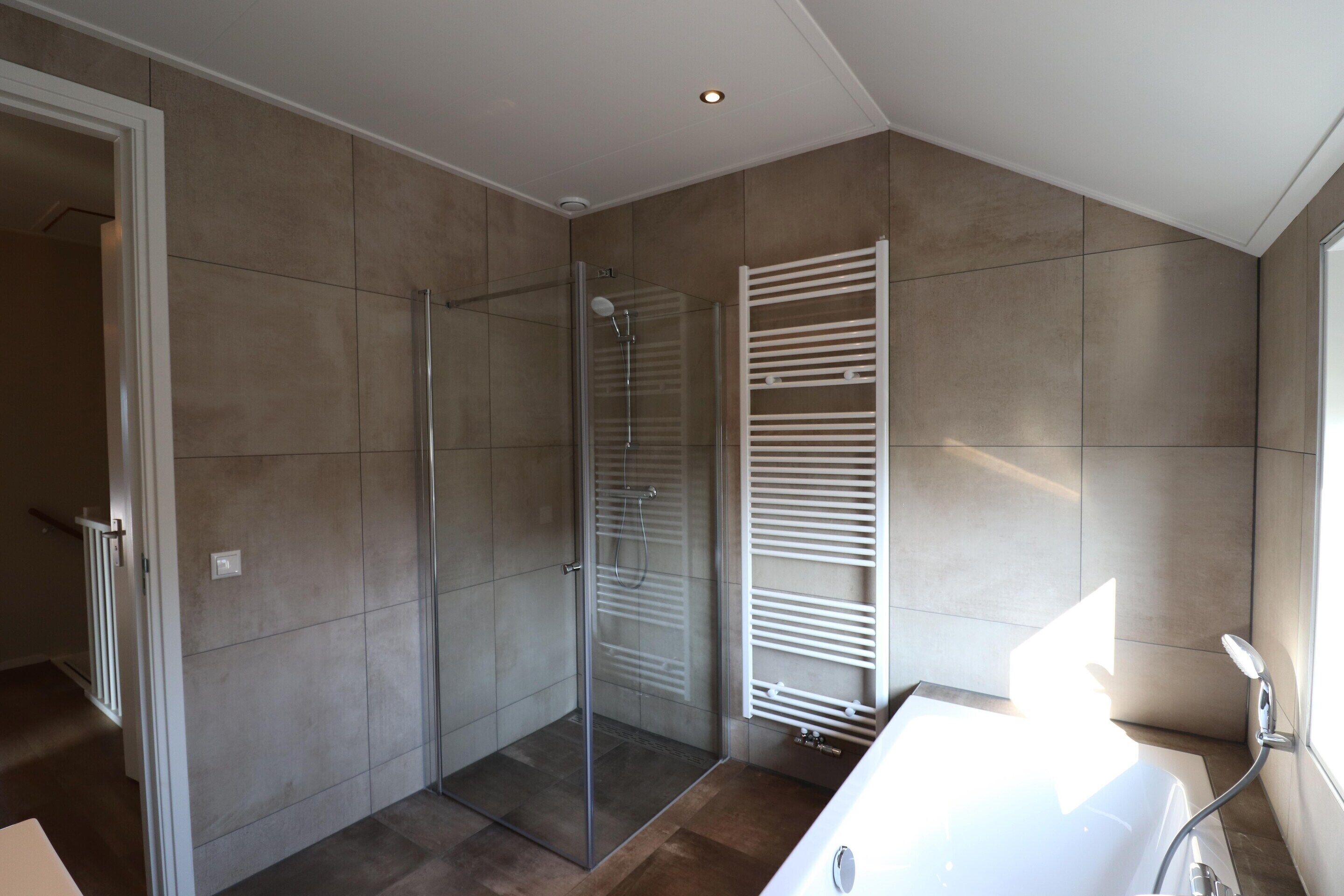 Un bagno moderno con cabina doccia in vetro, una vasca da bagno bianca e un porta asciugamani.