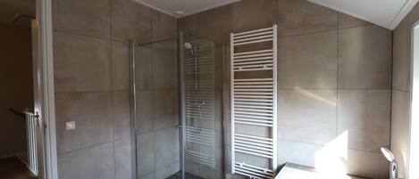 Un bagno moderno con cabina doccia in vetro, una vasca da bagno bianca e un porta asciugamani.