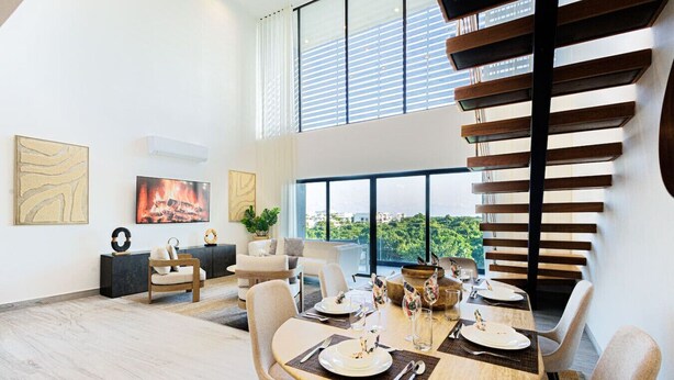 Un espace repas moderne avec une grande table dressée pour quatre personnes, entourée de sièges confortables.