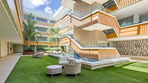 Un bâtiment moderne doté d’une cour intérieure, d’un espace extérieur aménagé pour s’asseoir et d’une piscine.