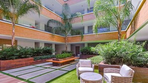 Une cour intérieure à plusieurs niveaux, dotée d’un espace extérieur aménagé avec des sièges, de la verdure et un design architectural moderne.