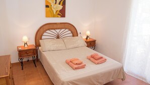 A bedroom with a bed, two bedside tables with lamps, a painting on the wall, and a window with curtains. - 3 Bedroom Ground FloorApartment (MOJACAR)
