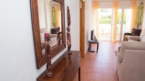A living room with a wooden cabinet, a large mirror, a sofa, and a television. - 3 Bedroom Ground FloorApartment (MOJACAR)