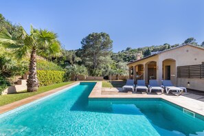 Ein Swimmingpool mit Liegestühlen, einer Palme und einem Gebäude mit Bögen.