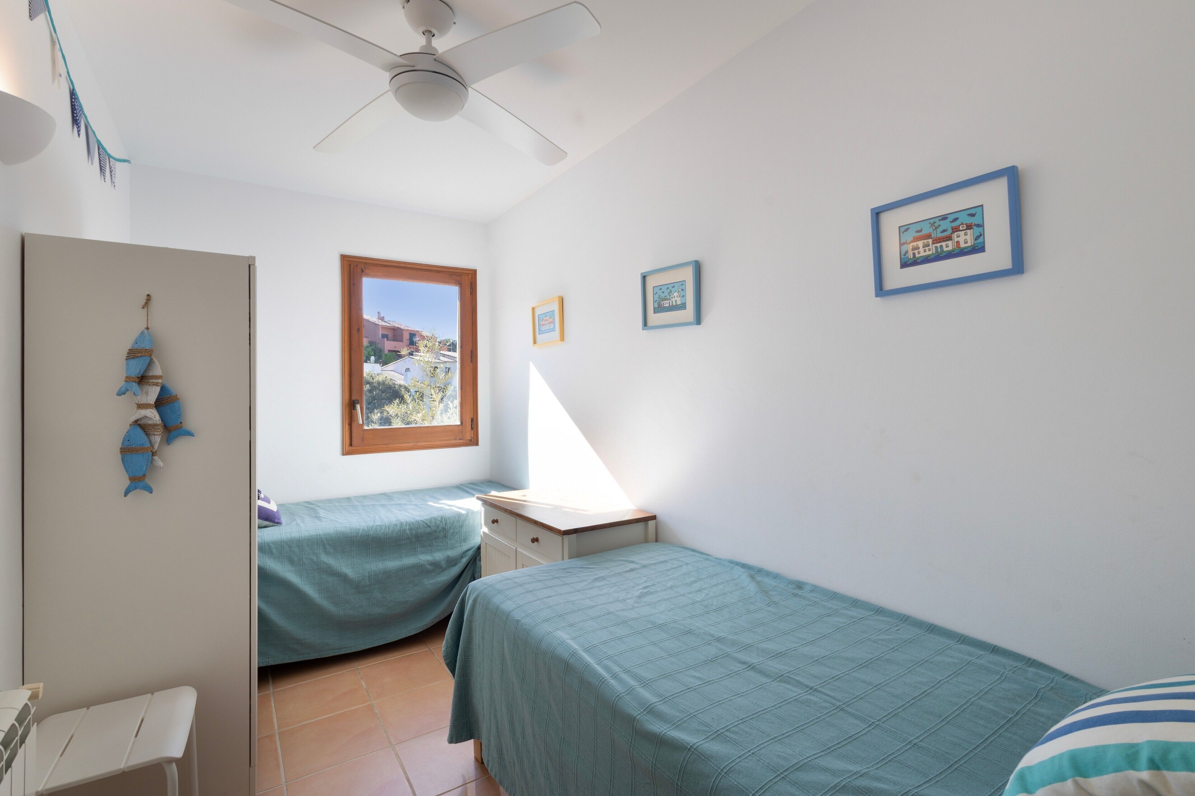 Un dormitorio con dos camas, un escritorio, un armario y un ventilador de techo.