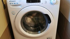 Eine Candy Smart Waschmaschine mit Digitalanzeige, Bedienfeld und einem Aufkleber mit der Aufschrift '6 MESI GRATIS'.