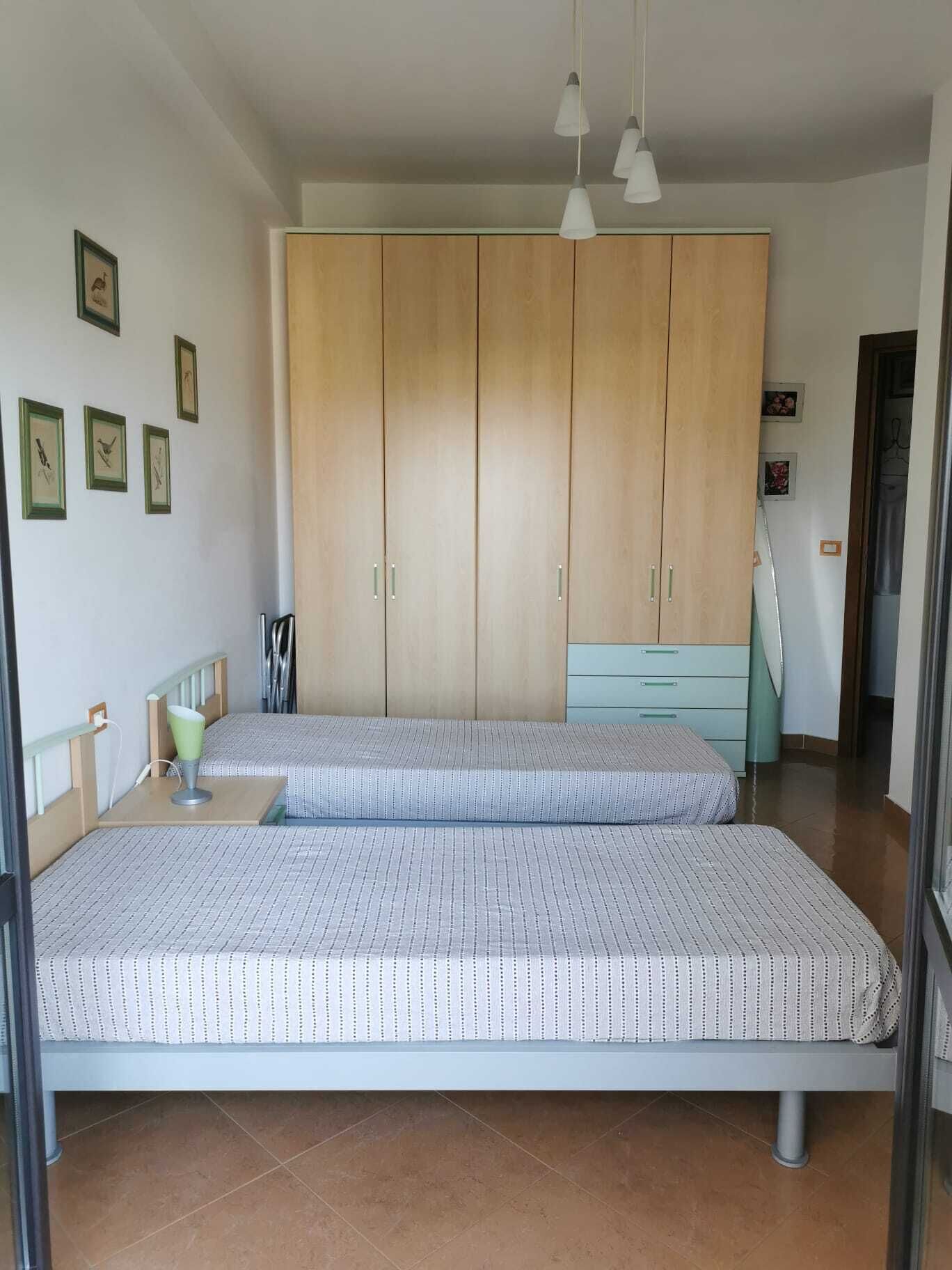Een slaapkamer met twee bedden, een kledingkast en een bureau.
