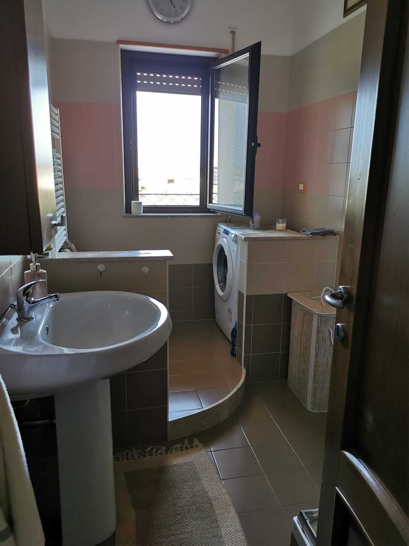 A compact bathroom with a sink, a washing machine, and a small cabinet.