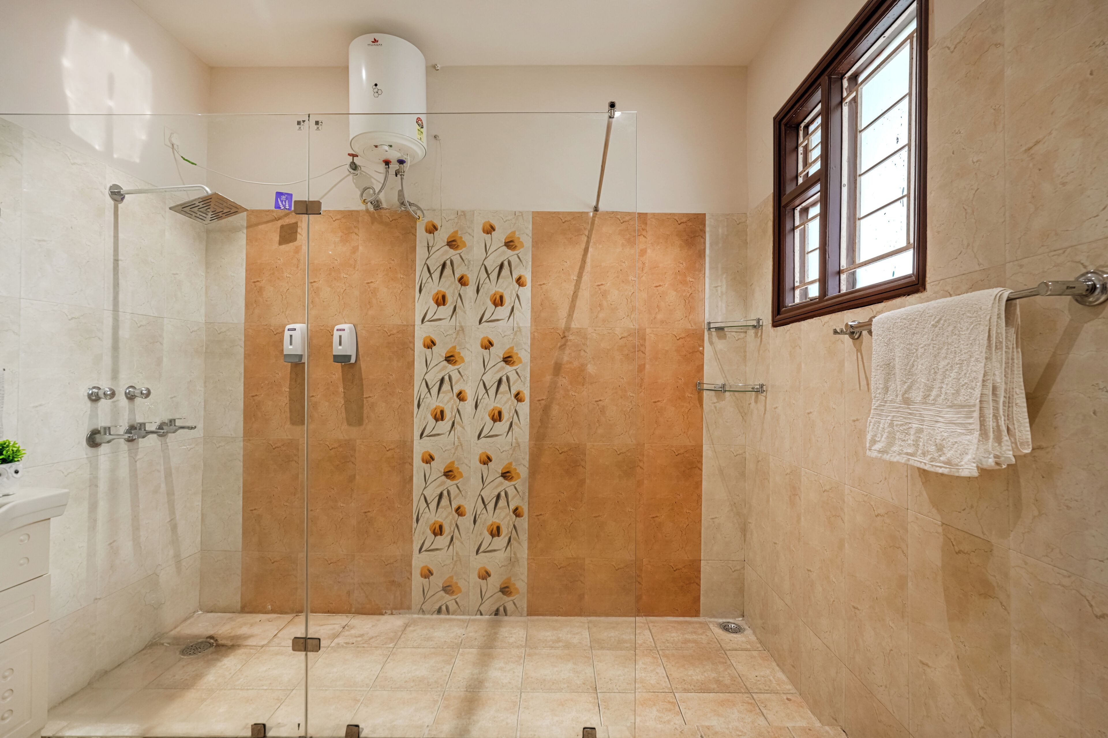 A shower area with a glass door, a hand dryer, and a towel rack.