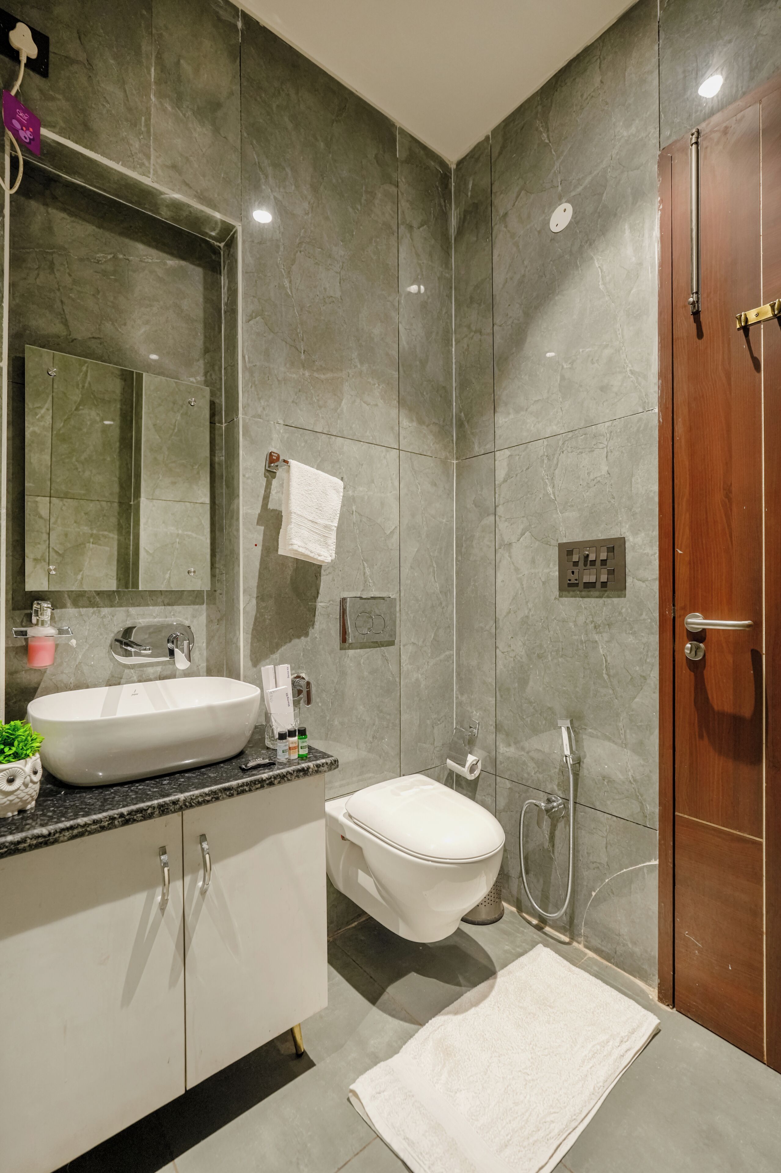 Un baño moderno con un espejo grande, un lavabo, un inodoro y una ducha.
