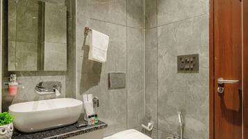 Un baño moderno con un espejo grande, un lavabo, un inodoro y una ducha.