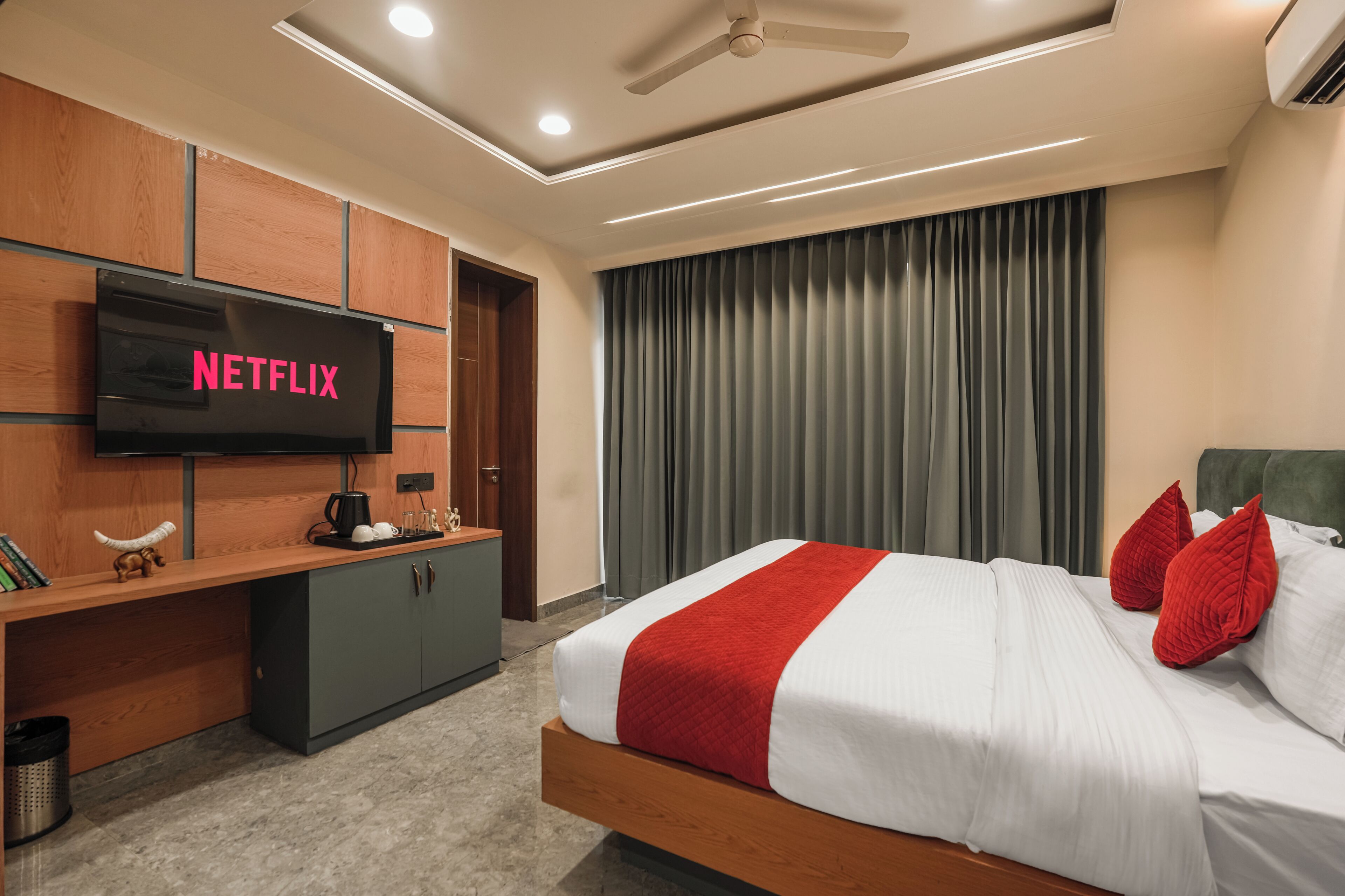 Quarto de hotel com uma cama, televisão, escrivaninha e armário.