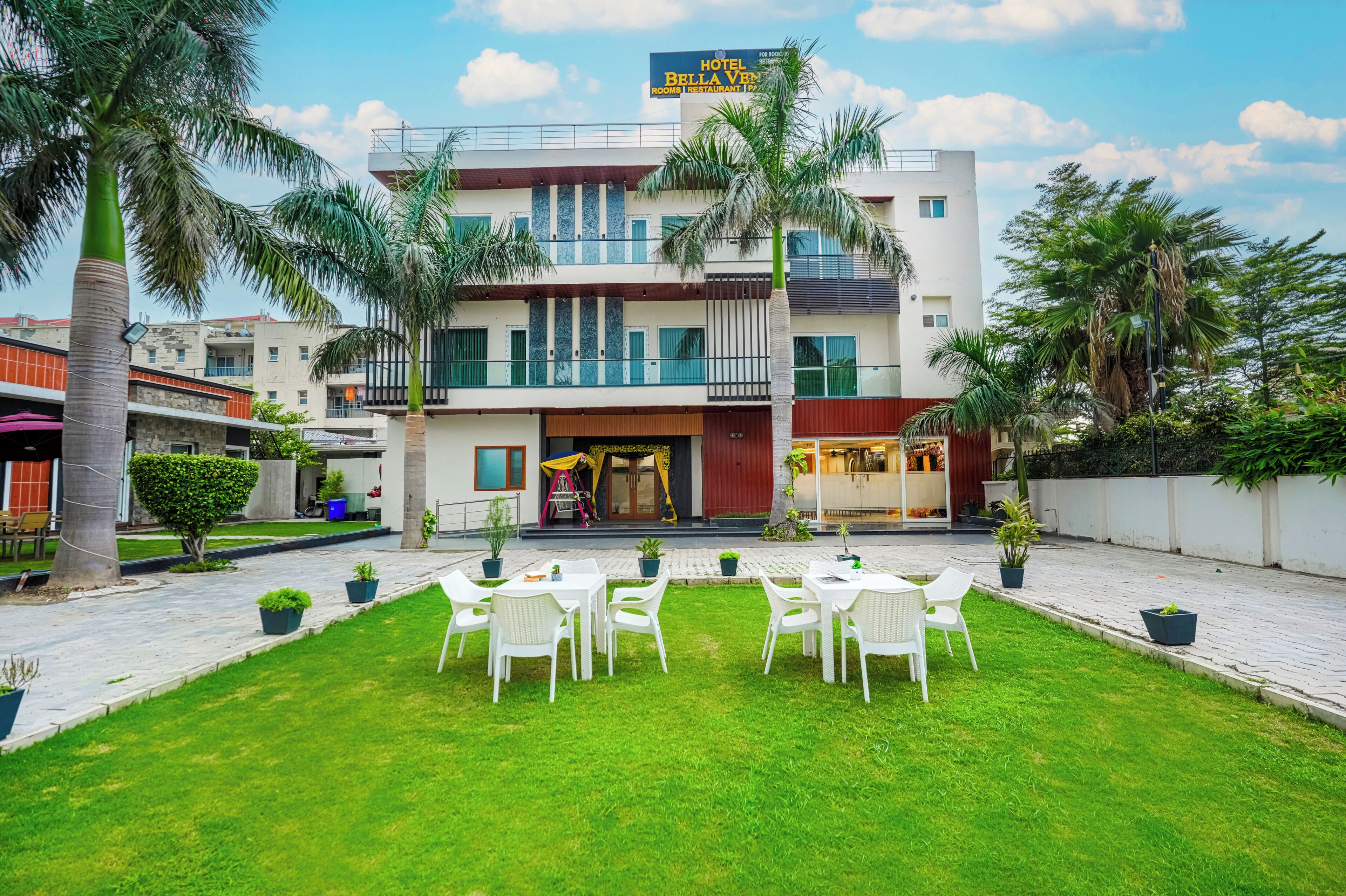 A hotel with a well-maintained lawn, outdoor seating area, and a visible restaurant.