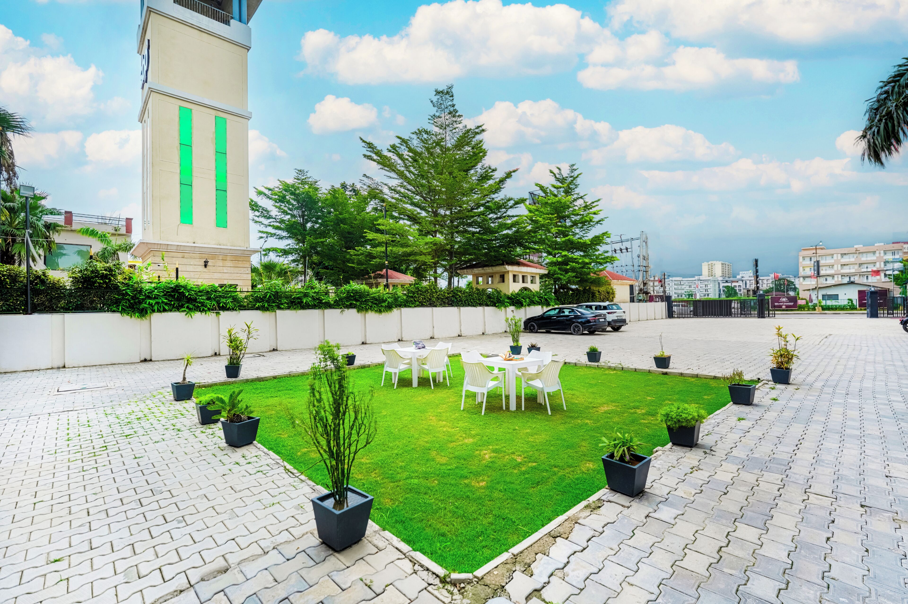 Un patio con césped, zona de estar y un edificio alto al fondo.