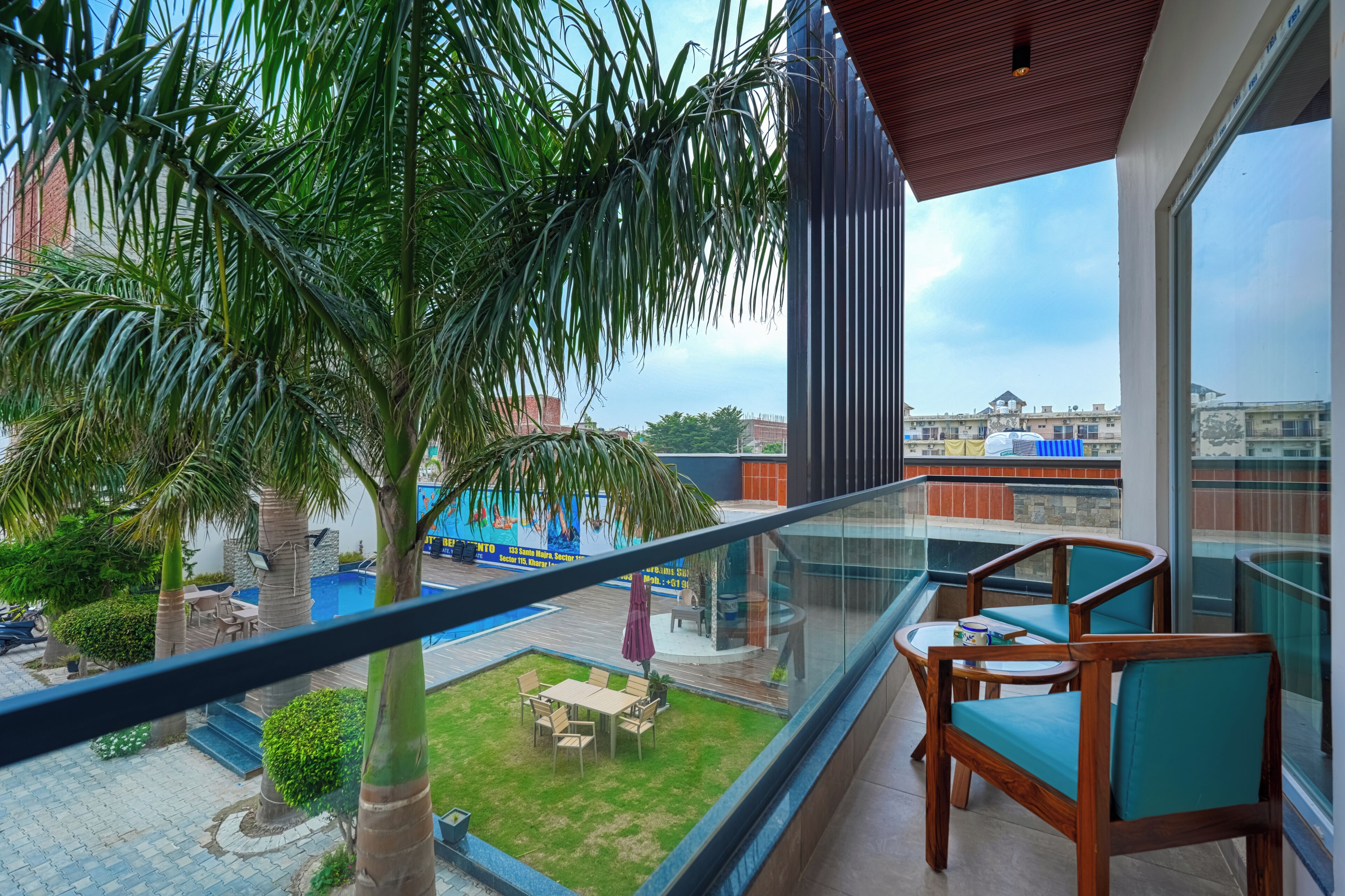 Un balcón con vistas a una piscina, palmeras y un paisaje urbano.
