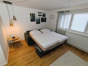 Un dormitorio con una cama, una mesita de noche con un marco de fotos y una ventana con persianas.
