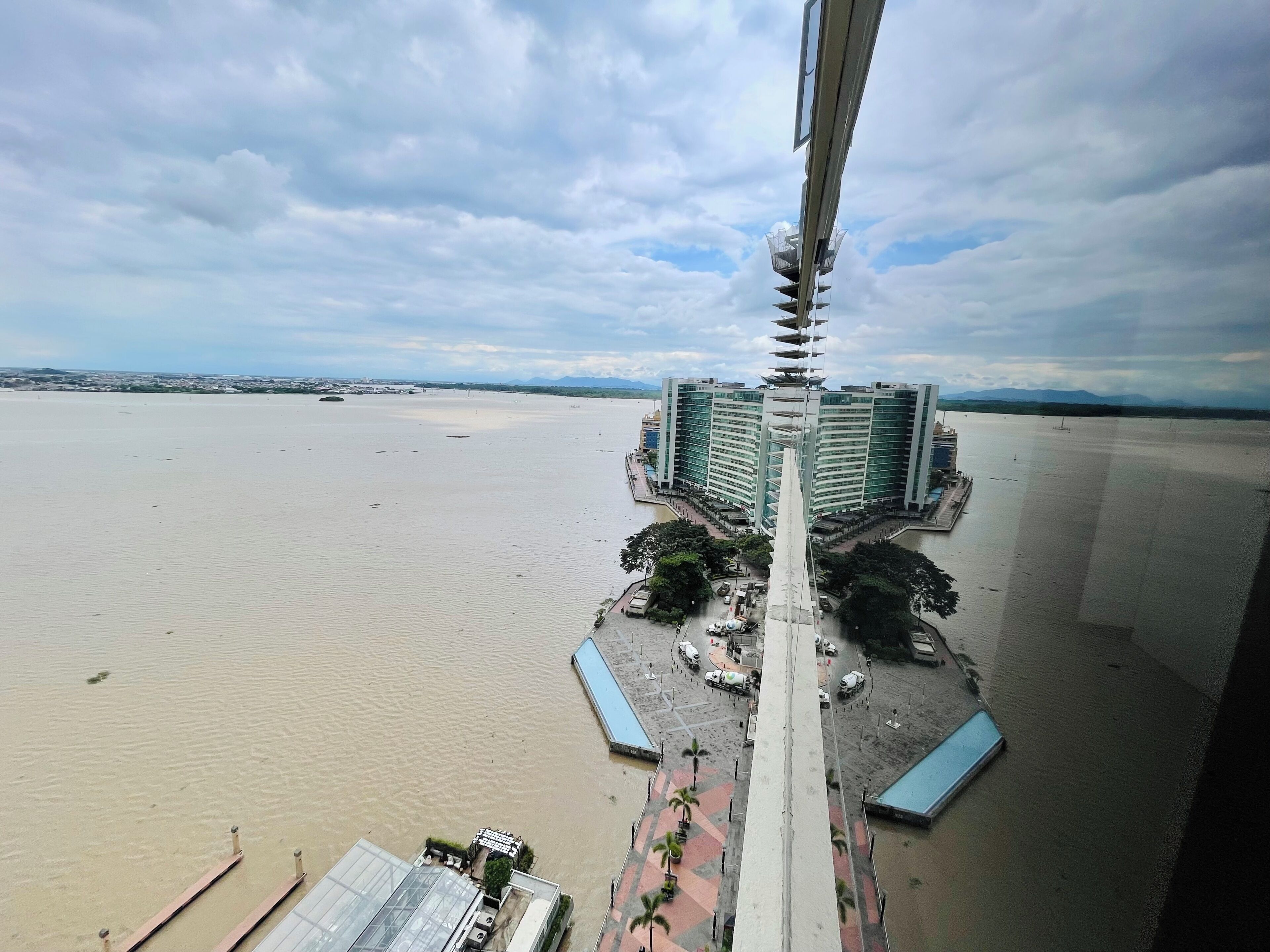 Un hôtel de grande hauteur offrant une vue sur le front de mer, doté d’une tour centrale et d’un espace paysager agrémenté de palmiers.