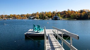 A wooden dock with chairs, a clear lake, and houses in the background. - Chester Back Harbour Exclusive providing direct access to water via private dock (Chester Basin)