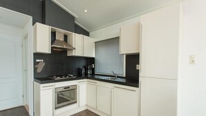 Een moderne keuken met witte kastjes, een zwart aanrecht, een ingebouwde oven en een rvs-afzuigkap.