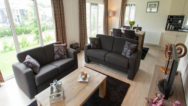 Een moderne woonkamer met twee banken, een salontafel en een eethoek met een tafel en stoelen.