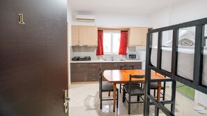 A compact kitchen with a dining area, a microwave, and a stove. - Vila Myrtaj (Ksamil)
