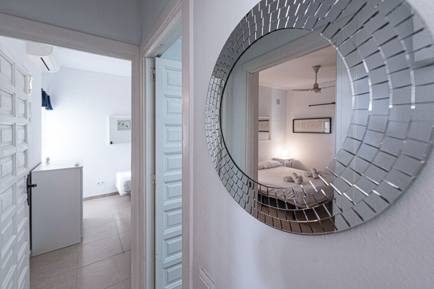 Una habitación moderna con un espejo redondo, una cama y una mesita de noche.