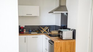 Een compacte keuken met witte kasten, een magnetron, een broodrooster en een koffiezetapparaat.