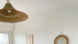 Een slaapkamer met een bed, een bedlampje, een spiegel aan de muur en een raam.