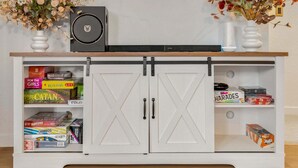 A white cabinet with two doors, a black speaker, and two vases with dried flowers. - Perch - AC Home w/ Sauna, Hot tub & Outdoor Seating! (Seattle)