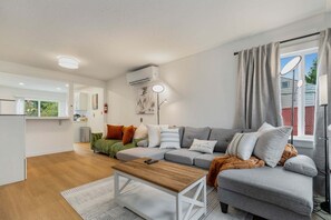 A modern living room with a grey sofa, a wooden coffee table, and a floor lamp. - Perch - AC Home w/ Sauna, Hot tub & Outdoor Seating! (Seattle)